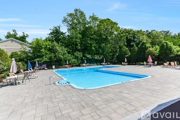 A pool surrounded by trees and chairs.