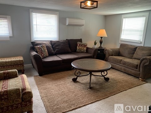 A living room with a brown couch, a round table, and a lamp on a side table.