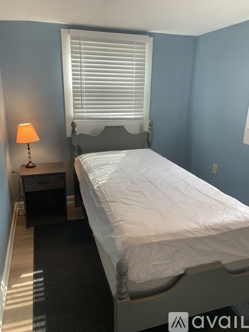 A bedroom with a bed, nightstand, and lamp.