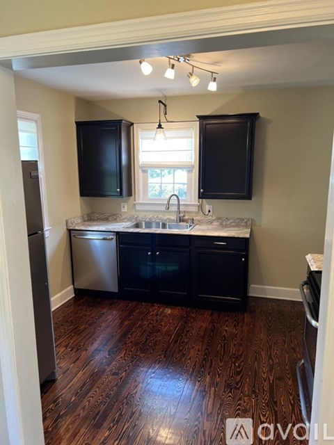 A kitchen with black cabinets and a wooden floor.