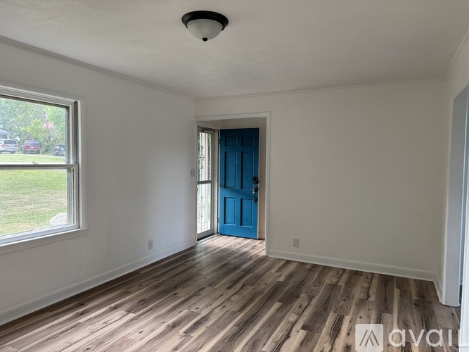 A room with a blue door and wooden flooring.