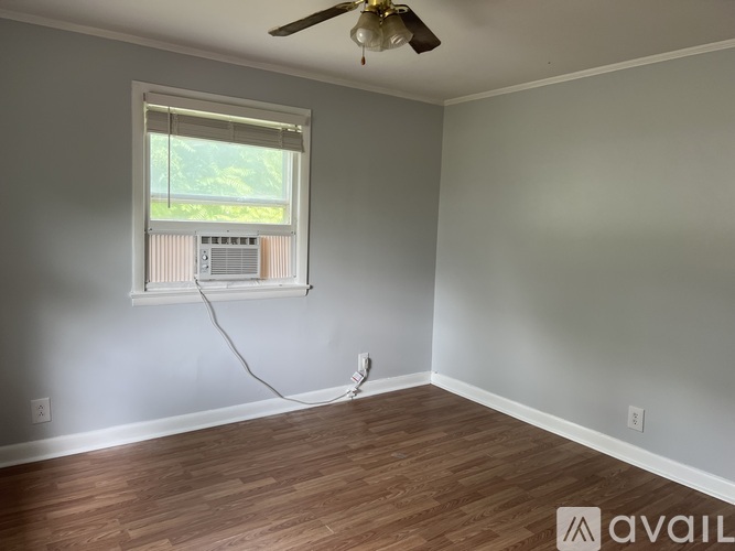 A room with a ceiling fan and a window with blinds.