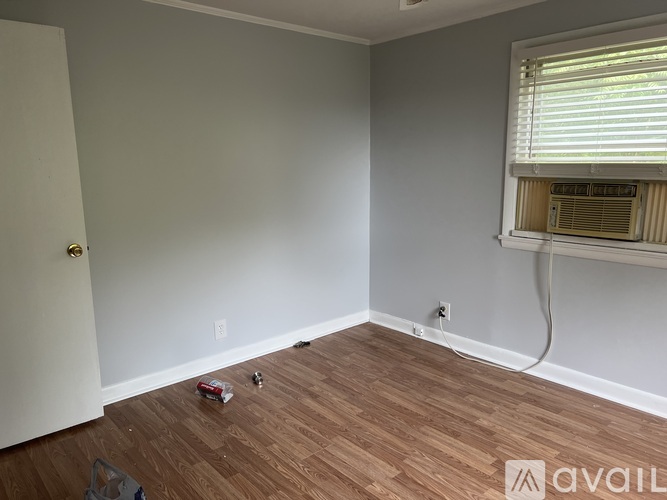 A room with wooden flooring and a window with blinds.