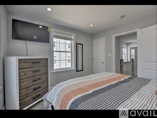 A bedroom with a large bed and a flat screen TV mounted on the wall.