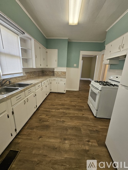 A kitchen with white cabinets and a wooden floor.