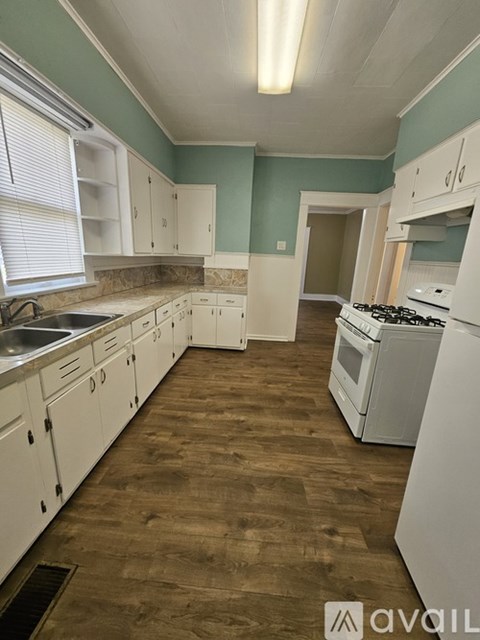 A kitchen with white cabinets and a wooden floor.
