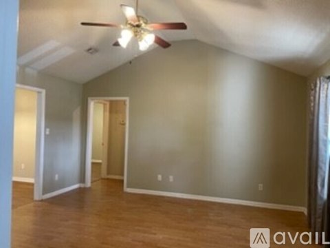 A room with a ceiling fan and wooden flooring.