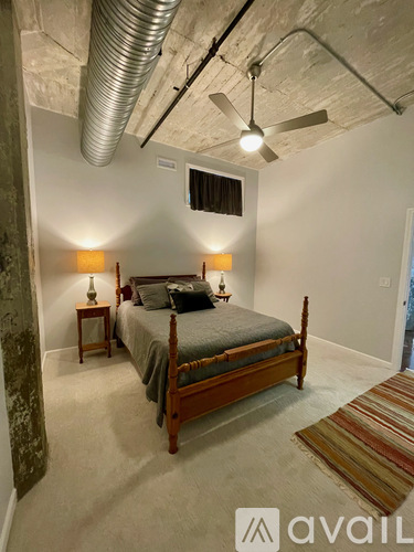 A bedroom with a bed, two lamps, and a rug.