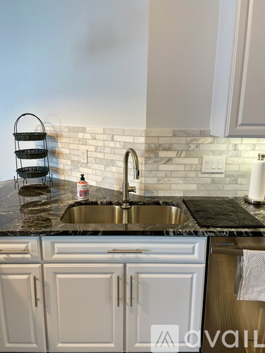 A kitchen with a sink and a bottle of dish soap on the counter.