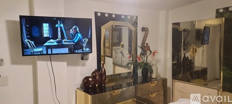 A television is mounted on a wall above a dresser.