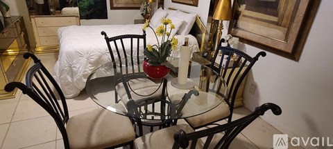 A table with chairs and a vase of flowers is in the foreground.