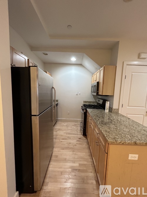 A kitchen with a granite counter top and wooden cabinets.