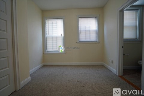 A room with a carpeted floor and two windows.