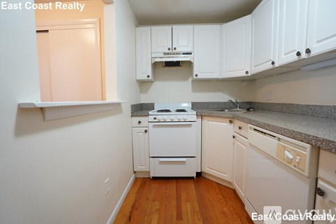 A kitchen with white cabinets and a stove top oven.