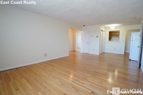 Empty room with wooden flooring and white walls.