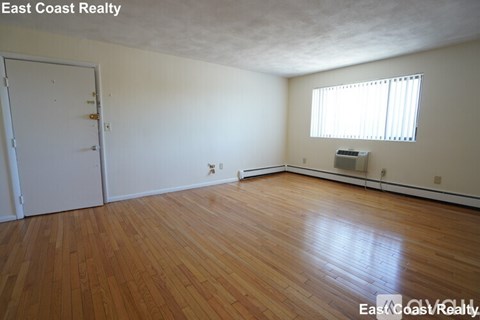 A room with wooden floors and a window with blinds.