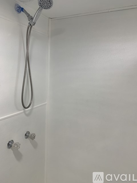 A white shower stall with a hose and a shower head.