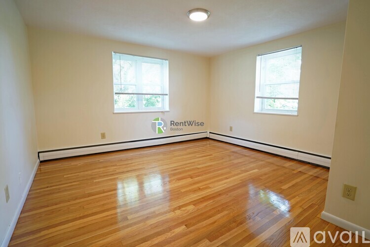 A room with wooden flooring and two windows, one of which has a sign that says "Renewiice".