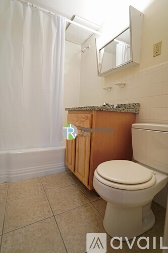 A white toilet in a bathroom with a wooden cabinet and a mirror above it.