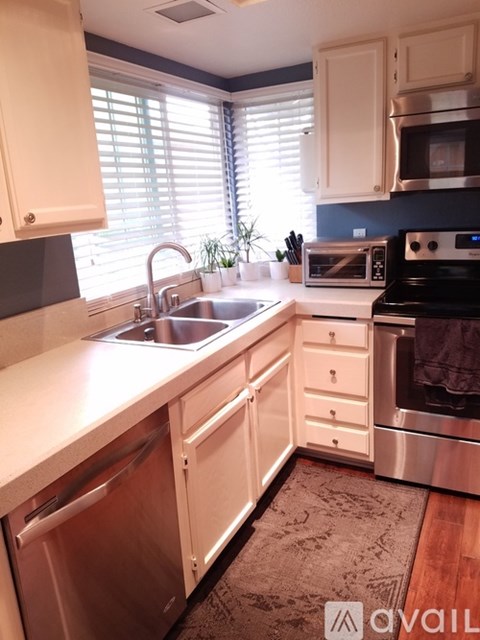 A kitchen with white cabinets and a stainless steel dishwasher.