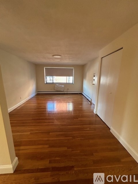 A long hallway with wooden floors and a window.