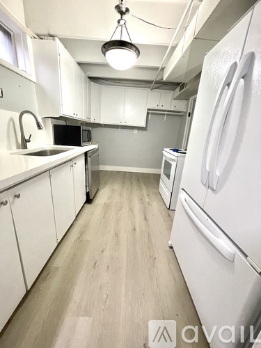 A kitchen with white cabinets and a white fridge.