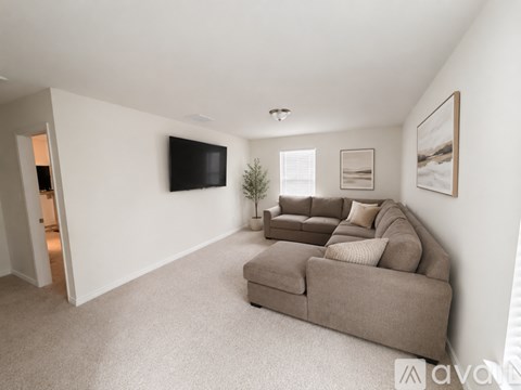 A living room with a grey couch and a flat screen TV mounted on the wall.