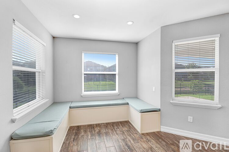 A room with a window seat and a view of a building outside.