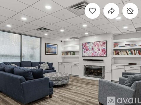 A living room with a dark blue couch, a white fireplace, and a painting on the wall.