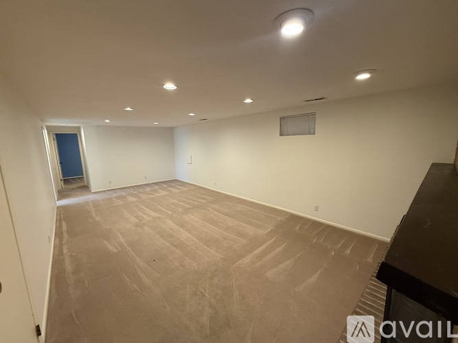A spacious room with a carpeted floor and a door on the left side.