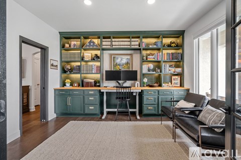 A living room with a black leather couch and a green bookshelf filled with books.
