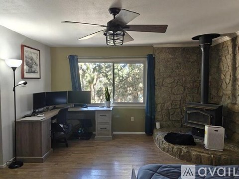 A room with a desk, chair, and a fan.