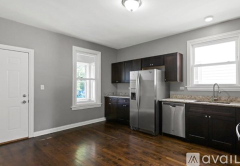 A kitchen with a refrigerator, sink, and cabinets.