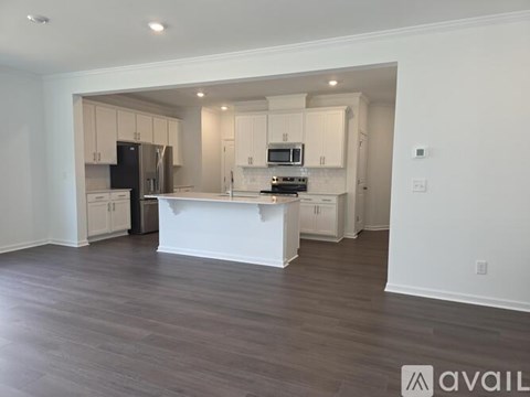 A kitchen with white cabinets and a wooden floor.