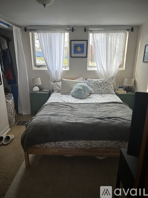 A bedroom with a bed, nightstands, and a window with curtains.