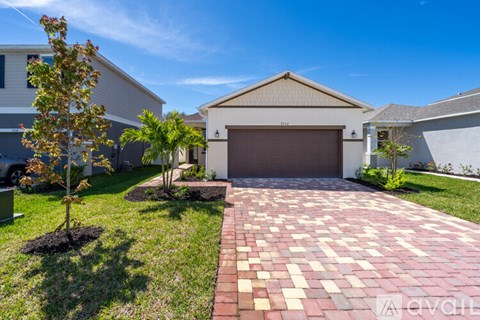 A house with a driveway and a tree in front of it.