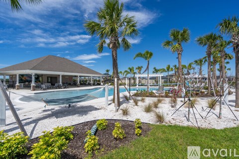 A pool surrounded by palm trees and a white building.