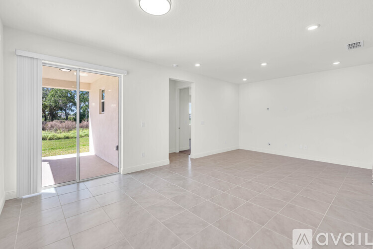 A spacious room with a tiled floor and a sliding glass door leading to a garden.