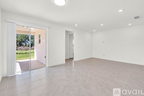 A spacious room with a tiled floor and a sliding glass door leading to a garden.