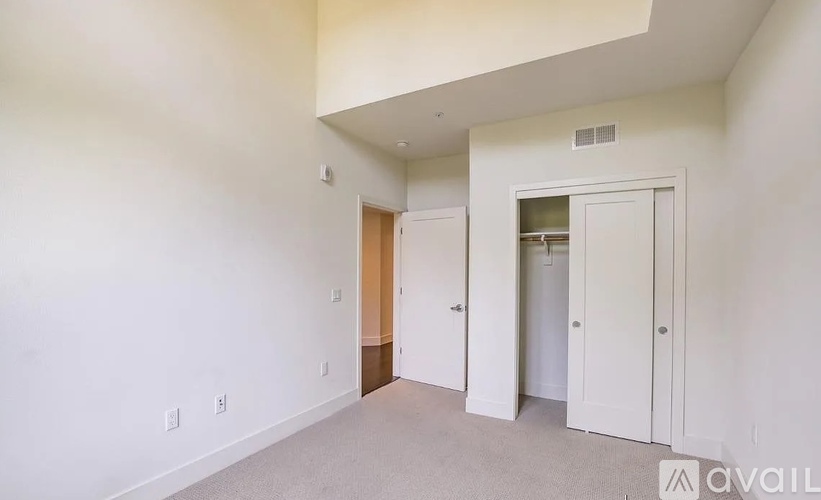 A spacious room with a carpeted floor and white walls.