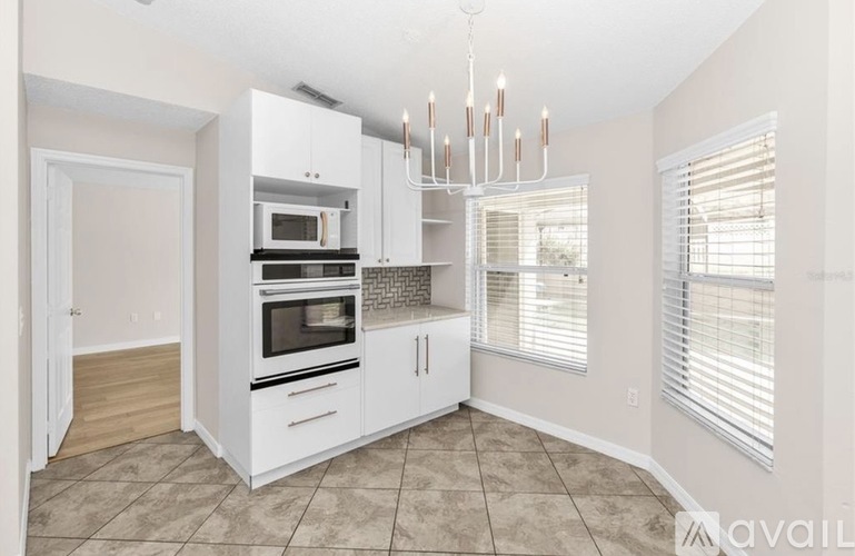 A kitchen with white cabinets and a chandelier.