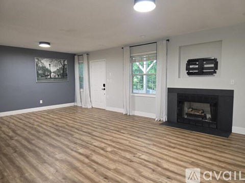 A spacious living room with a fireplace and a painting on the wall.