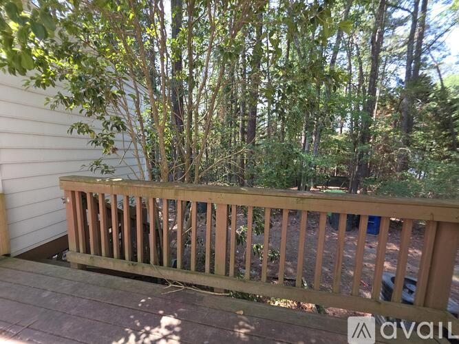 A wooden deck with a railing and a view of trees.