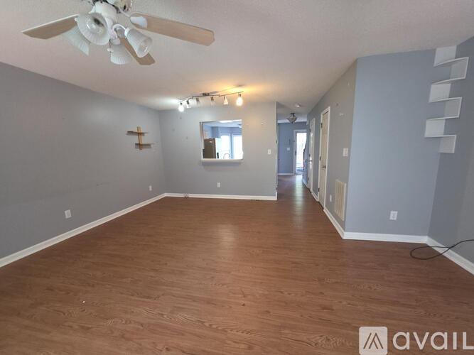 A spacious room with wooden flooring and a ceiling fan.