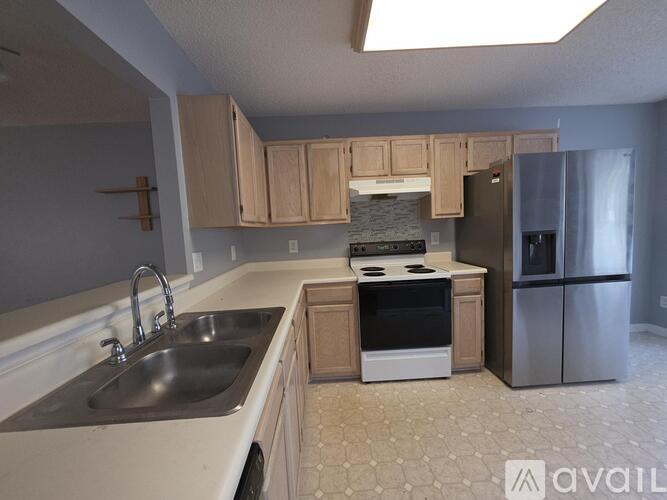 A kitchen with a stove, sink, and refrigerator.