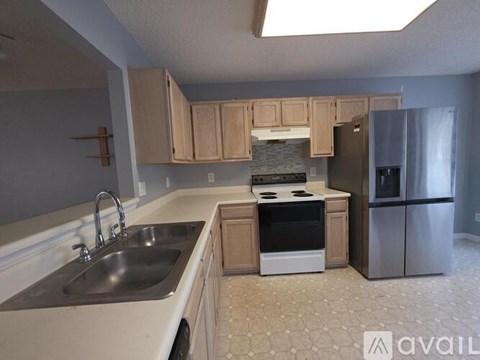 A kitchen with a stove, sink, and refrigerator.
