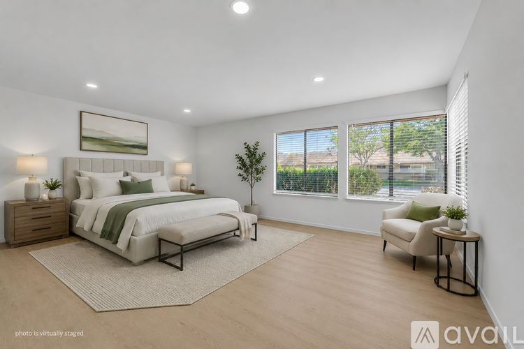 A bedroom with a large bed, a chair, and a small table.
