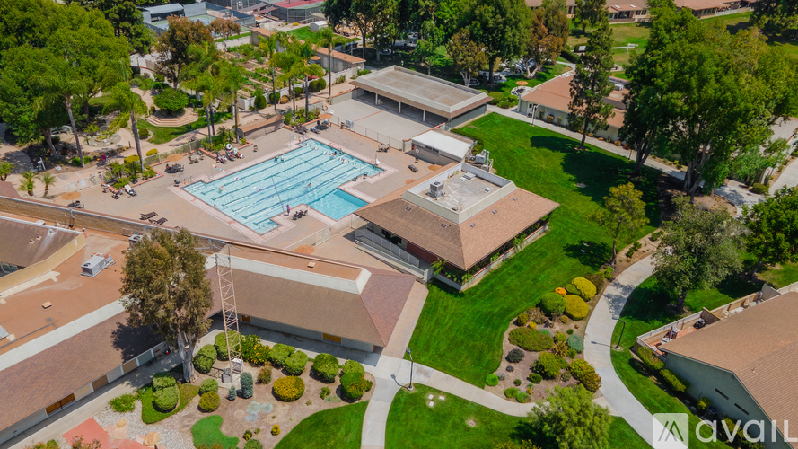 An aerial view of a swimming pool surrounded by buildings and trees.