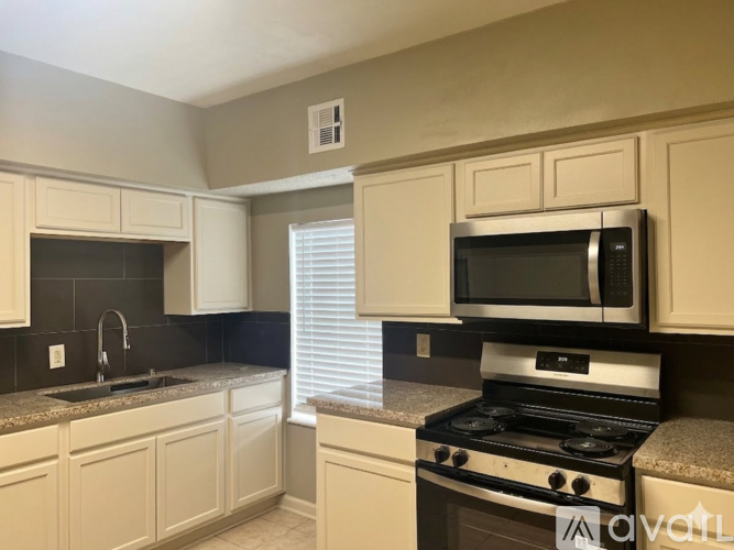 A kitchen with white cabinets and a black countertop.