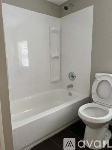 A white toilet sits next to a white bathtub in a bathroom.